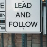 Photo of urban signage displaying 'Lead and Follow', emphasizing guidance and navigation.